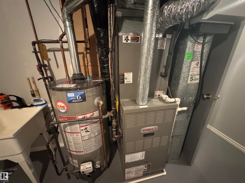 Utility area featuring a Lennox furnace, water heater, and a utility sink - 4502 55 Avenue, Vegreville, AB 