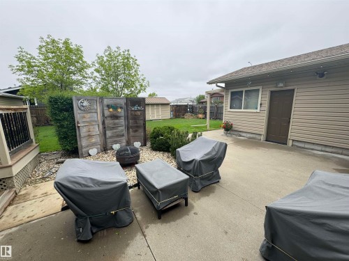 Concrete patio with a decorative privacy screen, fire pit, and a detached shed - 4502 55 Avenue, Vegreville, AB 