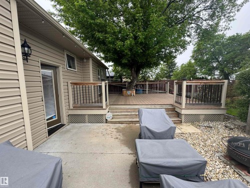 Multi-level wood-finish deck with integrated railing, accessible from a concrete patio - 4502 55 Avenue, Vegreville, AB 