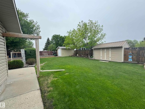 Expansive green lawn with two utility sheds, one featuring a metal roof - 4502 55 Avenue, Vegreville, AB 