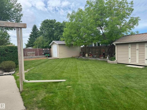 Spacious green lawn with a privacy fence, two storage sheds, and mature trees - 4502 55 Avenue, Vegreville, AB 