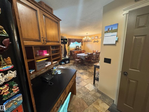 Built-in desk area featuring wood cabinetry, open shelving, and a dark countertop - 4502 55 Avenue, Vegreville, AB 