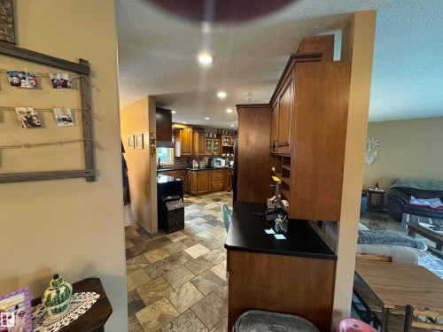 Kitchen featuring recessed lighting, a window, wood cabinetry, and stone-look tile flooring - 4502 55 Avenue, Vegreville, AB 