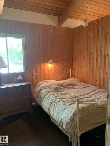 Room featuring wood-paneled walls and a matching wood-finish ceiling with exposed beams - #446 67432 Mcgrane Rd, Rural Lac La Biche County, AB 