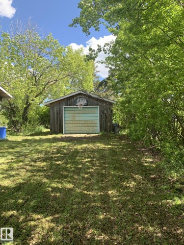 Detached garage with natural wood siding and a light-colored garage door - #446 67432 Mcgrane Rd, Rural Lac La Biche County, AB 