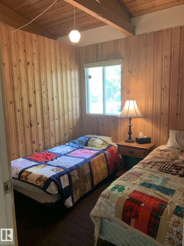 Room featuring knotty pine paneling, exposed wood beams, and a ceiling-mounted light fixture - #446 67432 Mcgrane Rd, Rural Lac La Biche County, AB 