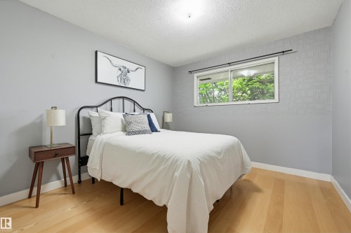 Light wood-finish flooring complements the neutral wall color and textured accent wall - 10712 52 Avenue, Edmonton, AB 