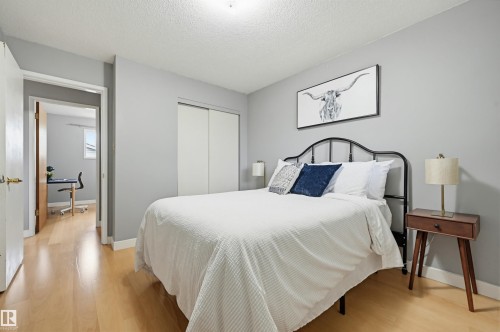 Bedroom featuring light wood-finish flooring, light gray walls, and white baseboards - 10712 52 Avenue, Edmonton, AB 