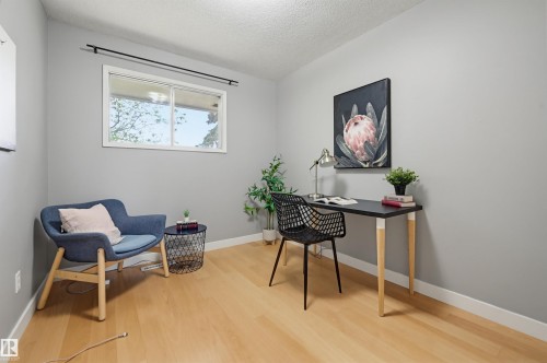 Light-filled room featuring wood-finish flooring, a white-framed window, neutral painted walls, and white baseboards - 10712 52 Avenue, Edmonton, AB 