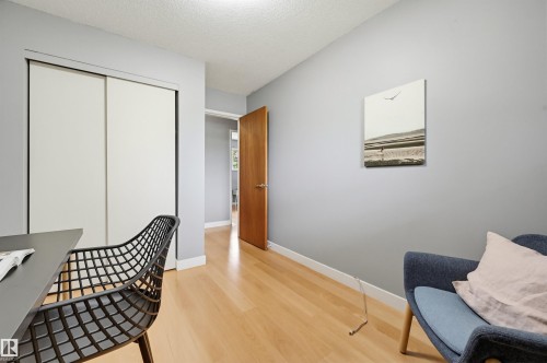 Room featuring wood-finish flooring, light gray walls, white baseboards, and a white ceiling - 10712 52 Avenue, Edmonton, AB 