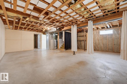Unfinished basement featuring exposed ceiling joists and concrete flooring - 10712 52 Avenue, Edmonton, AB 