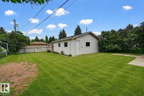 Detached garage with siding exterior, multiple windows, and a side access door - 10712 52 Avenue, Edmonton, AB 