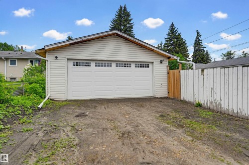 Detached garage featuring white panel siding and a white garage door with upper window inserts - 10712 52 Avenue, Edmonton, AB 