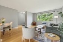 Spacious interior featuring light wood-finish flooring, a broad window overlooking mature greenery, and neutral wall tones - 10712 52 Avenue, Edmonton, AB 
