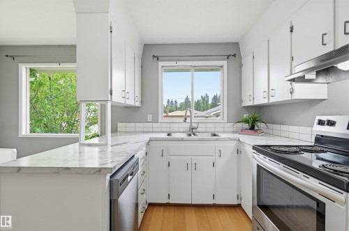 Kitchen featuring white cabinetry, light-toned wood-finish flooring, and white countertops with a subway tile backsplash - 10712 52 Avenue, Edmonton, AB 
