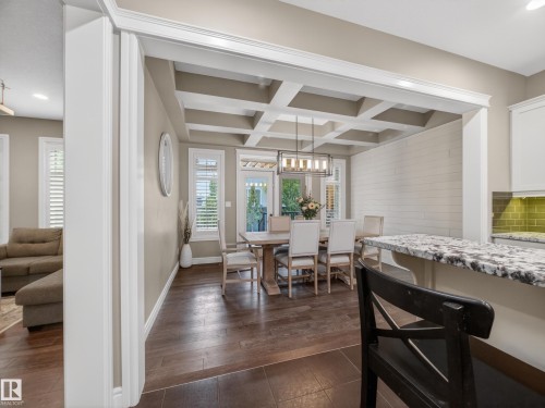 Formal dining area featuring a coffered ceiling, wood-finish flooring, and white plantation shutters - 5608 Soleil Boulevard, Beaumont, AB 