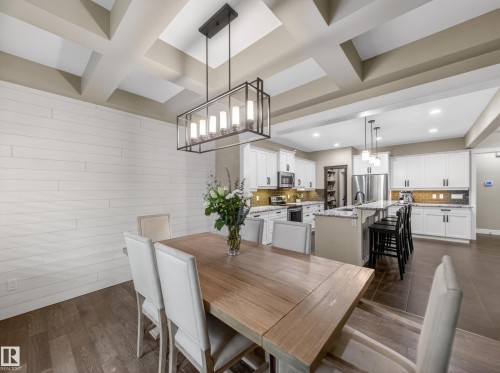 Open-concept dining area featuring a coffered ceiling and a linear chandelier - 5608 Soleil Boulevard, Beaumont, AB 