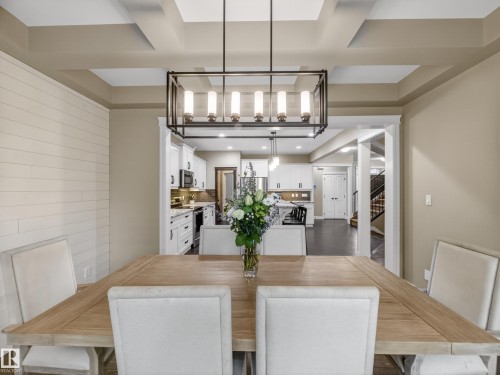 Dining area featuring a coffered ceiling and a contemporary linear chandelier - 5608 Soleil Boulevard, Beaumont, AB 
