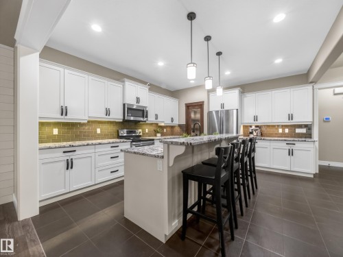Contemporary kitchen featuring white cabinetry, granite countertops, subway tile backsplash, and stainless steel appliances - 5608 Soleil Boulevard, Beaumont, AB 