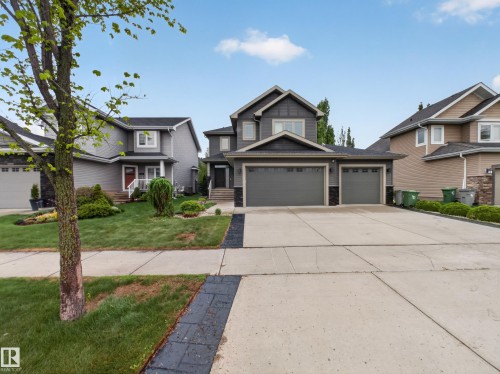 Modern two-story residence featuring a dark gray exterior, prominent gabled rooflines, and a spacious concrete driveway - 5608 Soleil Boulevard, Beaumont, AB 