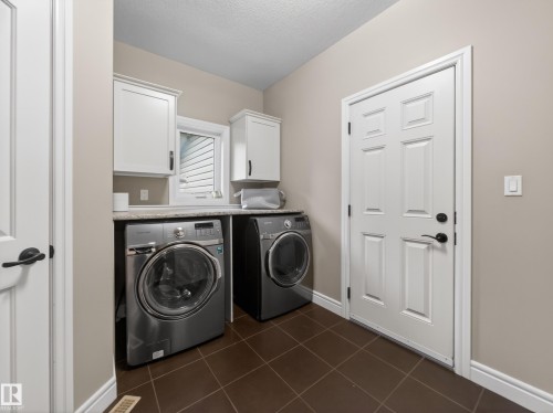 Laundry area featuring tile flooring, white cabinetry, a window, and solid core doors - 5608 Soleil Boulevard, Beaumont, AB 