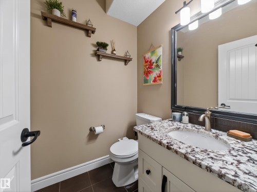 Bathroom featuring a vanity with a light-toned granite countertop, an undermount sink, and a brushed nickel faucet - 5608 Soleil Boulevard, Beaumont, AB 