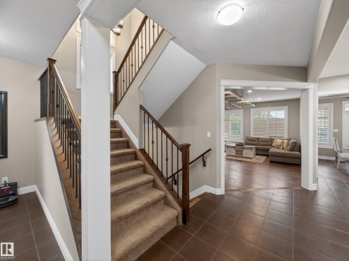 Carpeted staircase with dark wood handrails and wrought iron balusters - 5608 Soleil Boulevard, Beaumont, AB 