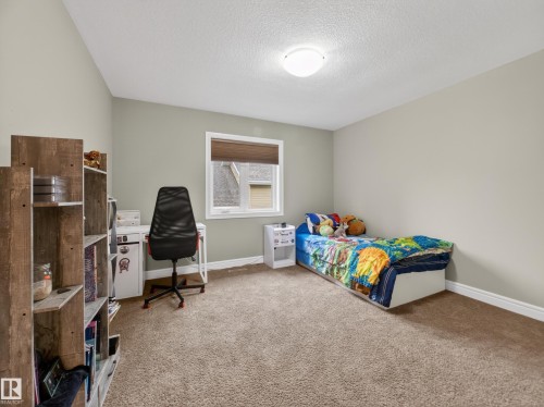 Carpeted room with a single window, white trim, and a ceiling-mounted light fixture - 5608 Soleil Boulevard, Beaumont, AB 