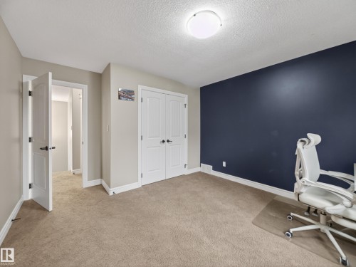 Carpeted room featuring a dark accent wall, white trim, and a flush mount ceiling light - 5608 Soleil Boulevard, Beaumont, AB 