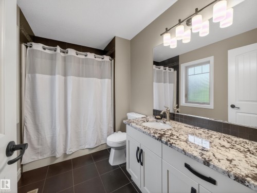 Bathroom featuring a white vanity with granite countertop, undermount sink, and matte black hardware - 5608 Soleil Boulevard, Beaumont, AB 