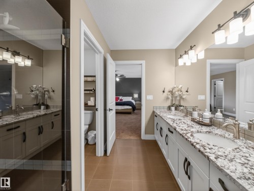 Bathroom featuring a dual vanity with granite countertops, undermount sinks, and brushed nickel fixtures - 5608 Soleil Boulevard, Beaumont, AB 