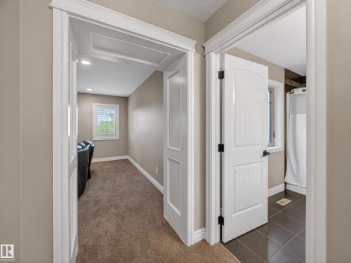 Hallway with white paneled doors, detailed trim work, and neutral wall paint - 5608 Soleil Boulevard, Beaumont, AB 