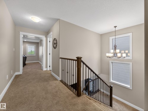 Upper-level landing featuring carpeted flooring and a decorative chandelier - 5608 Soleil Boulevard, Beaumont, AB 