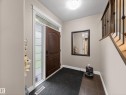 Entryway featuring a dark wood-finish door with an arched panel, a full-length sidelight with textured glass, and a transom window - 5608 Soleil Boulevard, Beaumont, AB 