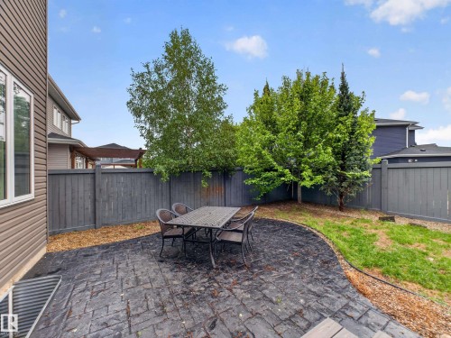 Private backyard featuring a stamped concrete patio, partial lawn, and mature trees - 5608 Soleil Boulevard, Beaumont, AB 