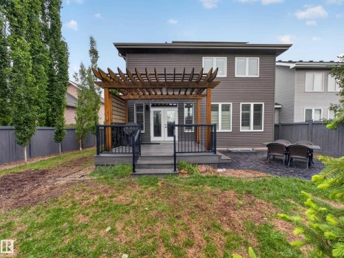 Rear exterior featuring a spacious deck with a wood pergola, dark composite decking, and black railings - 5608 Soleil Boulevard, Beaumont, AB 