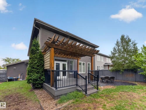 Rear exterior featuring a composite deck with black metal railings, a wood pergola, and double patio doors - 5608 Soleil Boulevard, Beaumont, AB 