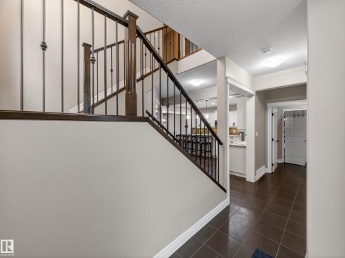 Grand staircase with dark wood-finish handrails and wrought iron balusters - 5608 Soleil Boulevard, Beaumont, AB 