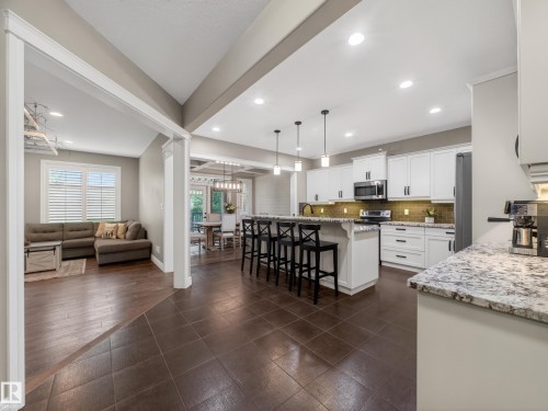 Gourmet kitchen featuring white shaker cabinetry, stainless steel appliances, granite countertops, and a subway tile backsplash - 5608 Soleil Boulevard, Beaumont, AB 