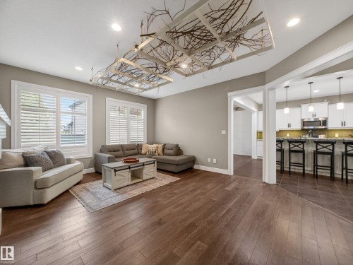Spacious living area featuring wood-finish flooring, recessed lighting, and a decorative ceiling installation - 5608 Soleil Boulevard, Beaumont, AB 