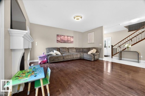 Spacious living area featuring rich wood-finish flooring and a white decorative fireplace mantel - 1326 Cunningham Drive, Edmonton, AB 