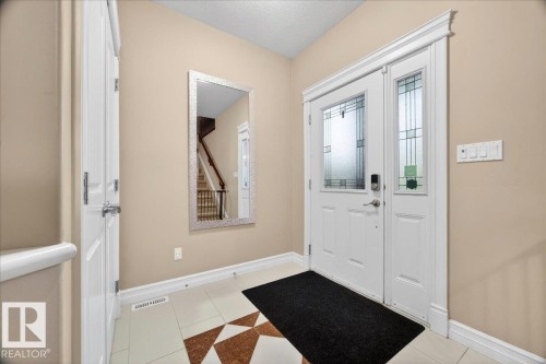 Entryway featuring a white door with decorative glass inserts, a coordinating sidelight, and a tiled floor with a geometric pattern - 1326 Cunningham Drive, Edmonton, AB 