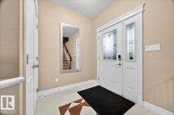 Entryway featuring a white door with decorative glass inserts, a coordinating sidelight, and a tiled floor with a geometric pattern - 