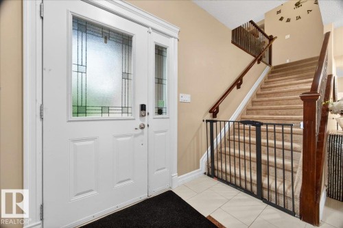 Entryway featuring a white paneled door with decorative glass inserts, a matching sidelight, and tiled flooring - 1326 Cunningham Drive, Edmonton, AB 