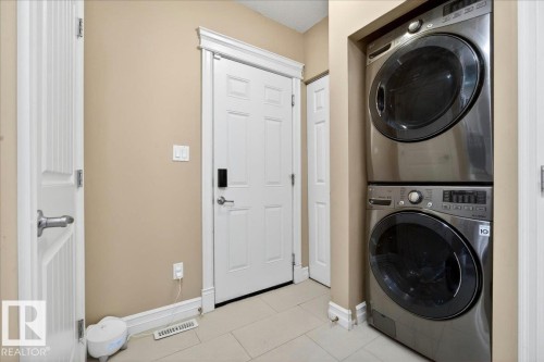 Integrated laundry area featuring a stacked washer and dryer, solid panel doors, and neutral wall tones - 1326 Cunningham Drive, Edmonton, AB 