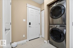 Integrated laundry area featuring a stacked washer and dryer, solid panel doors, and neutral wall tones - 