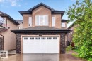 Two-story residence featuring a multi-pane garage door, stone veneer accents, and stucco siding - 1326 Cunningham Drive, Edmonton, AB 
