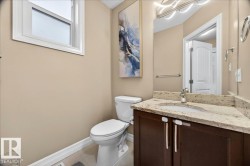Powder room featuring a corner vanity with a stone countertop, an integrated sink, and dark wood cabinetry - 