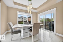 Dining area featuring a contemporary chandelier, tray ceiling, and light tile flooring - 