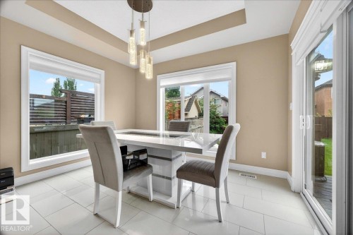 Recessed ceiling with an elegant pendant light fixture, large windows, and a sliding glass door - 1326 Cunningham Drive, Edmonton, AB 